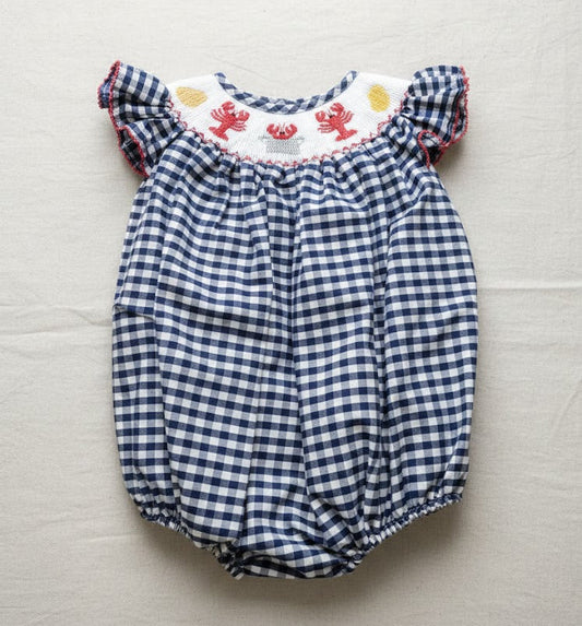 Blue and white checkered baby romper with ruffled top on a light gray background